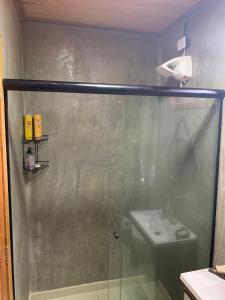 a shower with a glass door next to a sink at Chalé Ubá in Novo Airão