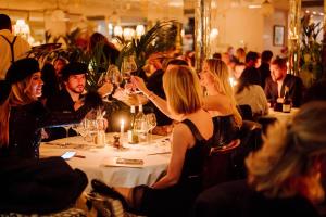 un groupe de personnes assises à une table avec des verres à vin dans l'établissement Hôtel Thoumieux, à Paris