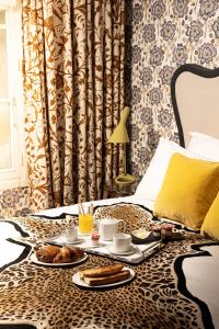 パリにあるホテル トゥミユのベッドの上に食べ物を置いた朝食用テーブル