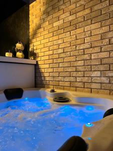 a hot tub with blue water in front of a brick wall at Apartman Stefan Lux in Vrdnik