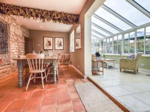 a conservatory with a table and chairs and windows at Barebones Farm in Winchcombe