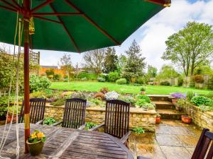 a table with an umbrella in a garden at Barebones Farm in Winchcombe