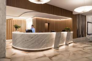 a woman standing at a reception desk in a lobby at Primavera Jastrzębia Góra in Jastrzębia Góra