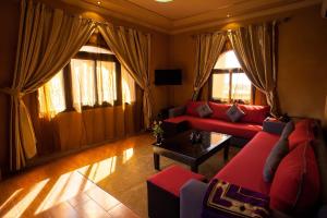 Charming apartment - secure and close to Marrakech no69 في تهنوت: غرفة معيشة مع أرائك ونوافذ حمراء