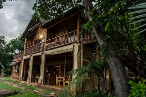 a wooden house with a porch and a tree at Hartbeespoortdam Lodge in Hartbeespoort