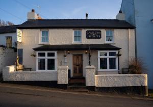 a white building with a sign on the front of it at The Rum Shack Manorbier Castle Inn in Manorbier