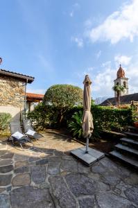 un patio con sombrilla, 2 sillas y un faro en Rustico al Sole - Just renewed 1bedroom home in Ronco sopra Ascona en Ronco sopra Ascona