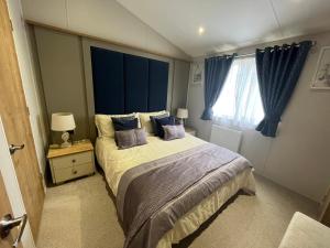 a bedroom with a large bed and a window at Kestral Court Lodge, Scratby - California Cliffs, Parkdean, sleeps 6, bed linen and towels included, wrap around decking - no pets in Scratby