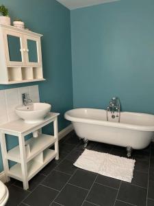 a bathroom with a white tub and a sink at Large coastal cottage, private indoor pool, hut tub, sauna and steam pod in Weymouth +20 photos