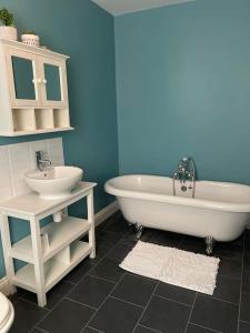 a bathroom with a white tub and a sink at Large coastal cottage, private indoor pool, hut tub, sauna and steam pod in Weymouth