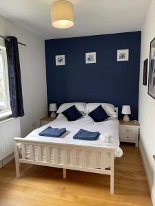 a bedroom with a white bed with blue walls at Large coastal cottage, private indoor pool, hut tub, sauna and steam pod in Weymouth