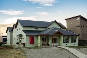 una casa verde con techo negro en Hostería Vertical Lodge en El Chaltén