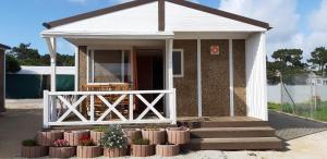 a small house with a porch and a fence at Parque de Campismo da Praia da Barra in Gafanha da Nazaré