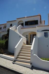 a white house with stairs in front of it at Renovated Vale do Milho Golf Apartment with sea view in Carvoeiro