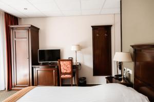 ein Hotelzimmer mit einem Bett und einem TV in der Unterkunft De Lunterse Boer in Lunteren