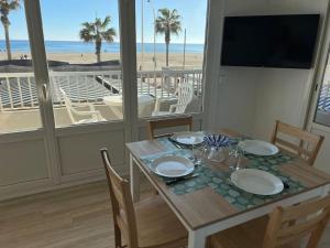 comedor con mesa y vistas a la playa en Le CARROUSEL - Apt VUE MER - Plage à 10 M - CLIM - WIFI, en Canet-en-Roussillon