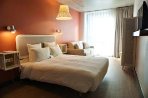 um quarto com uma cama, uma cadeira e uma janela em OKKO Hotels Paris La Défense em Nanterre