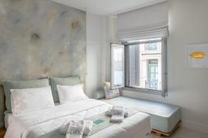 a bedroom with a large white bed and a window at Ciel Suites Athens in Athens