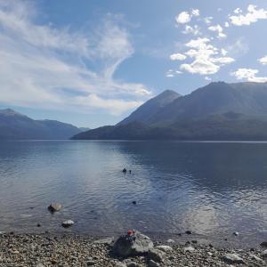 un par de personas nadando en un gran cuerpo de agua en Casita del lago en San Carlos de Bariloche