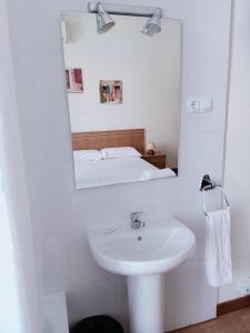 a white bathroom with a sink and a mirror at Hostal Miralva in Madrid
