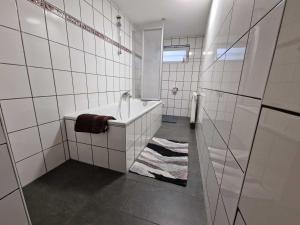 a white tiled bathroom with a tub and a shower at Ferienwohnung mit Smart-TV in Burscheid