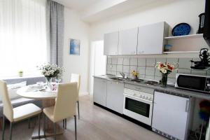 eine Küche mit weißen Schränken und einem Tisch mit Stühlen in der Unterkunft Ferienwohnung mit Smart-TV in Burscheid