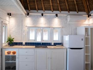 a kitchen with white cabinets and a white refrigerator at Seaside Cottage, Gili Air in Gili Islands