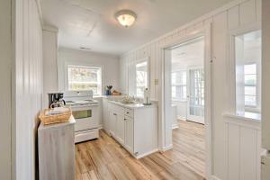 a kitchen with white appliances and wooden floors and windows at Romantic Waterfront Abode with Patio and Dock! in Deltaville
