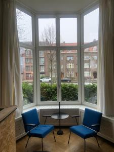 2 sillas y una mesa frente a una gran ventana en HS68-apartment, en Maastricht