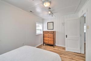 a white bedroom with a bed and a wooden dresser at Romantic Waterfront Abode with Patio and Dock! in Deltaville