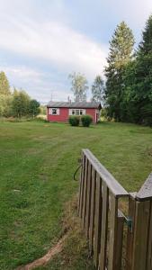 a fence in a yard with a red house at Stuga vad vatten in Åsarp