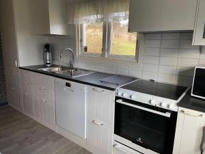 een keuken met witte kasten, een wastafel en een fornuis bij Cottage Båstad/Bjäre in Båstad