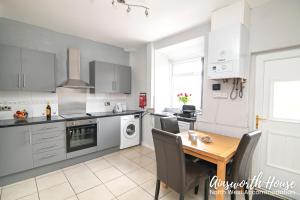 a kitchen with a wooden table and a dining room at Ainsworth House Serviced Accommodation in Bolton