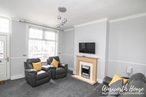 a living room with two chairs and a fireplace at Ainsworth House Serviced Accommodation in Bolton