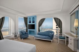 a bedroom with a bed and two chairs and a window at Al Habtoor Grand Resort, Autograph Collection in Dubai