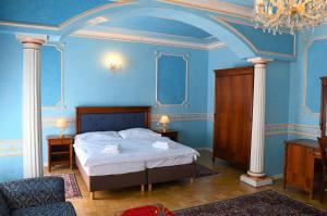 sypialnia z łóżkiem z niebieskimi ścianami i żyrandolem w obiekcie Hotel Renesance Krasna Kralovna w Karlowych Warach