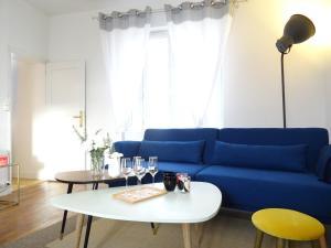 een woonkamer met een blauwe bank en een tafel bij Square-bnb - Duplex à 10min de Disneyland Paris in Montévrain
