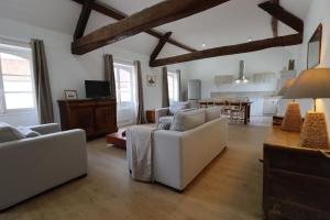 a living room with white couches and a kitchen at Château du Mesnil Soleil , gites et chambres d'hôtes in Damblainville