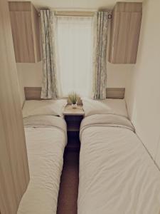 Duas camas num pequeno quarto com uma janela em The beach retreat, Lido Beach, Prestatyn em Prestatyn