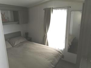 a white bedroom with a bed and a window at The beach retreat, Lido Beach, Prestatyn in Prestatyn