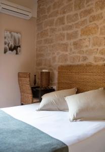 a bedroom with a white bed with a brick wall at Vilosell Wine Hotel in El Vilosell