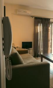 a living room with a couch and a television at Baia Blu Apartments in Syvota