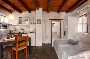 1 dormitorio con cama, mesa y cocina en White River Cottages - rustic minimalist holiday houses, en Makrí Gialós