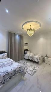 a bedroom with two beds and a chandelier at luxury apartment - Prince majed park in Jeddah