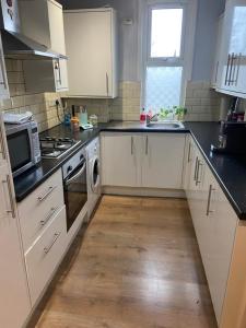 a kitchen with white cabinets and a wooden floor at Cozy home in Croydon