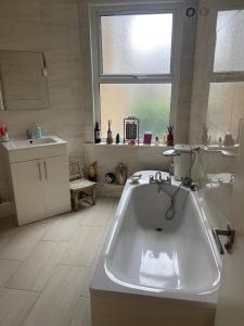 baño con bañera, lavabo y ventana en Cozy home en Croydon
