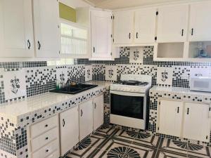 una cocina con armarios blancos y azulejos blancos y negros en City View Accommodations, en Roseau