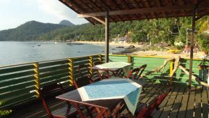uma mesa e cadeiras num deque ao lado de uma praia em Pousada Gabriel em Praia de Araçatiba