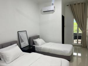 two beds in a hotel room with a window at Laena Homestay in Kangar
