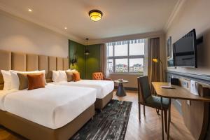 um quarto de hotel com duas camas e uma secretária em Sarovar Portico Srinagar em Srinagar